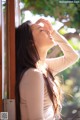 A woman looking out of a window with her eyes closed.