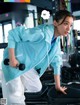 A woman in a blue jacket is working out in a gym.