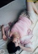 A woman laying on top of a bed in a pink dress.