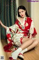 A woman in a red and white kimono sitting on the floor.