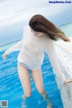 A woman in a white shirt and blue shorts standing in a pool.