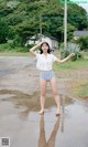 A woman standing in a puddle of water with her arms outstretched.