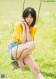 A woman sitting on a swing in a grassy field.