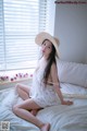 A woman sitting on a bed wearing a straw hat.