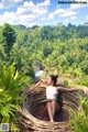 A woman sitting in a wicker basket on top of a hill.