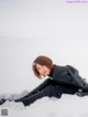 A woman laying in the snow in a black coat.