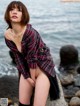 A woman sitting on a rock by the water.