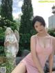 A woman in a pink dress sitting next to a statue.