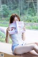 A woman sitting on a window sill reading a book.