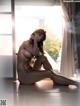 A nude woman sitting on the floor in front of a window.