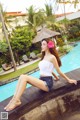 A woman sitting on the edge of a swimming pool.