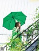 A woman in a green coat holding an umbrella.