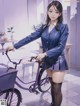 A woman in a school uniform standing next to a purple bike.