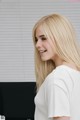 A woman with long blonde hair standing in front of a computer.