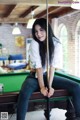 A woman sitting on top of a pool table.