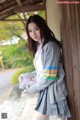 A woman in a school uniform leaning against a wall.